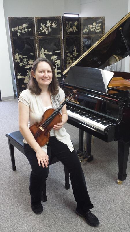 Smiling violinist seated in front of piano